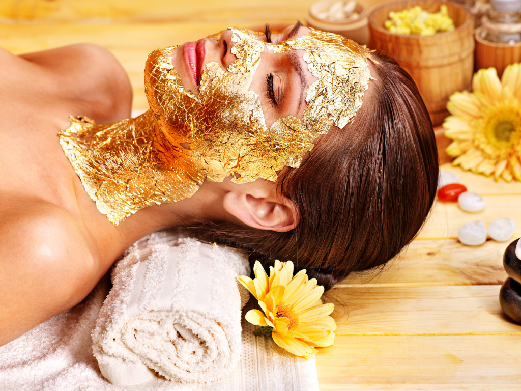 Woman getting gold facial mask.