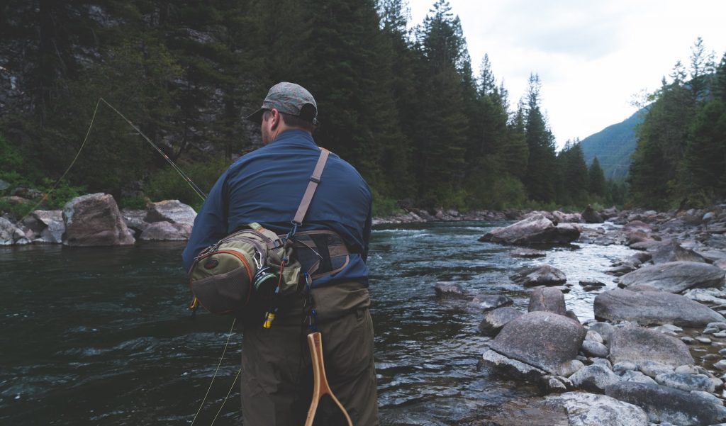 man fishing in rocky river